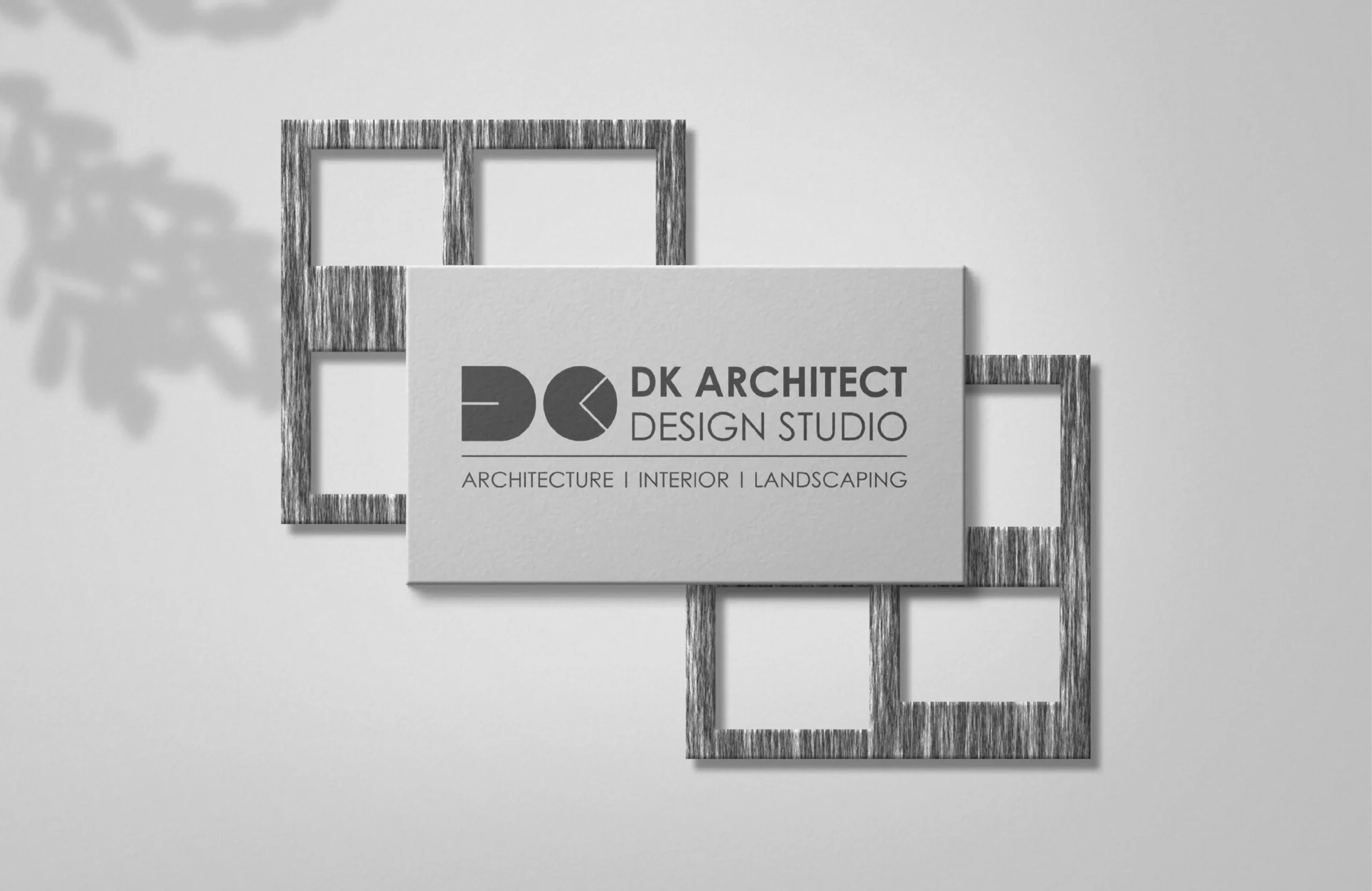 DK Architect Design Studio wall-mounted branding sign with logo plaque on a clean grey wall and geometric frame background.