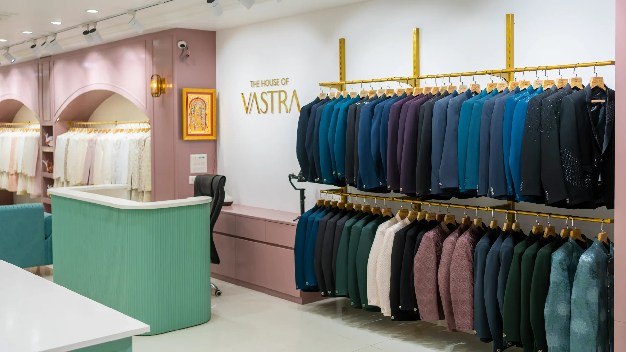 Reception area of House Of Vastra ethnic fashion showroom with pastel interiors, branded wall, and premium menswear display