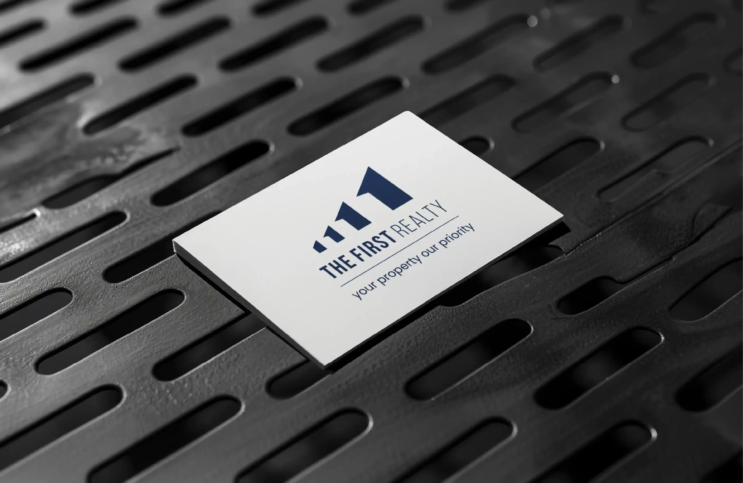 Business card mockup featuring The First Realty logo design and real estate branding.
