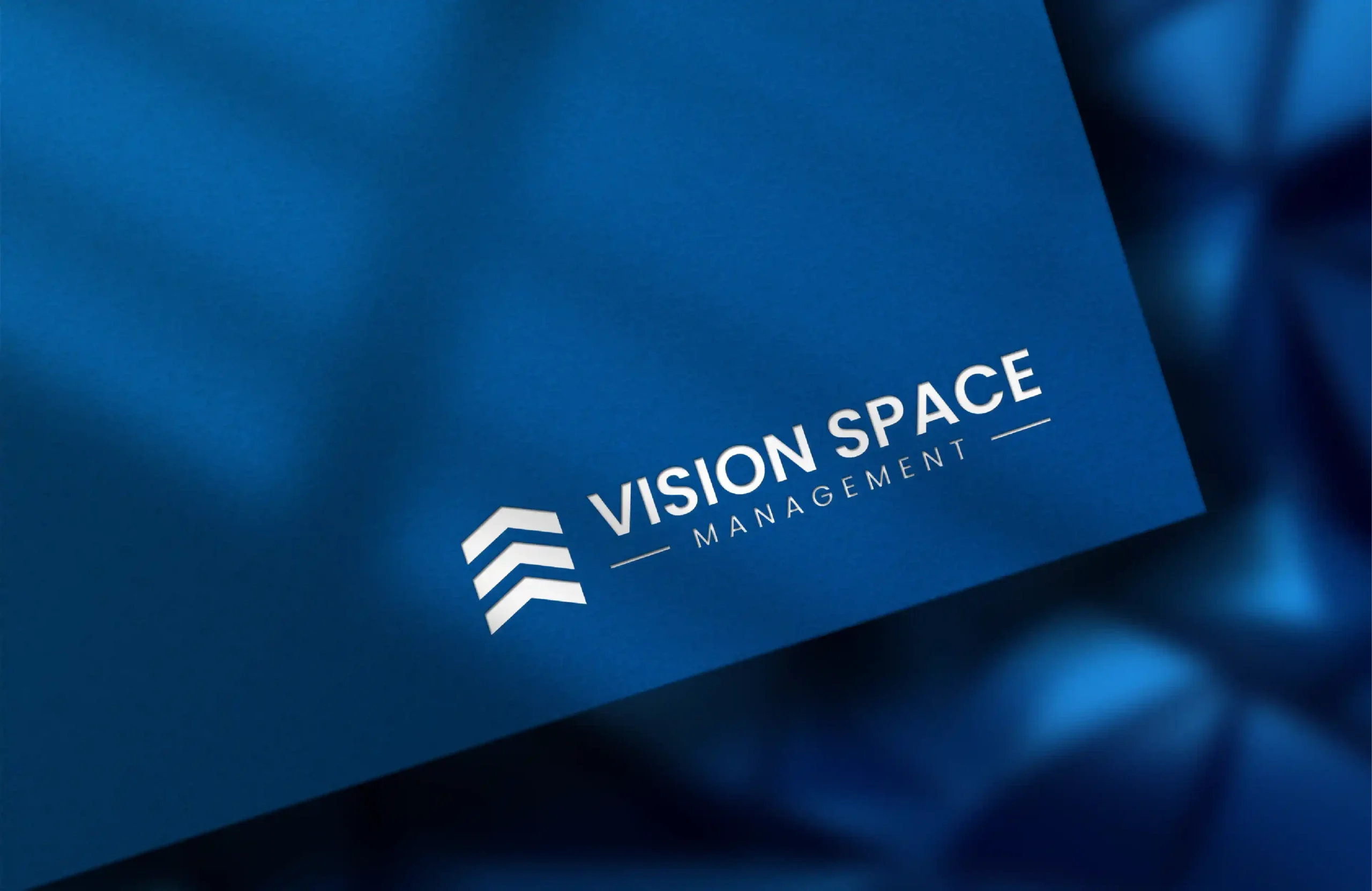 Business card mockup featuring the Vision Space Management logo in white on a blue background