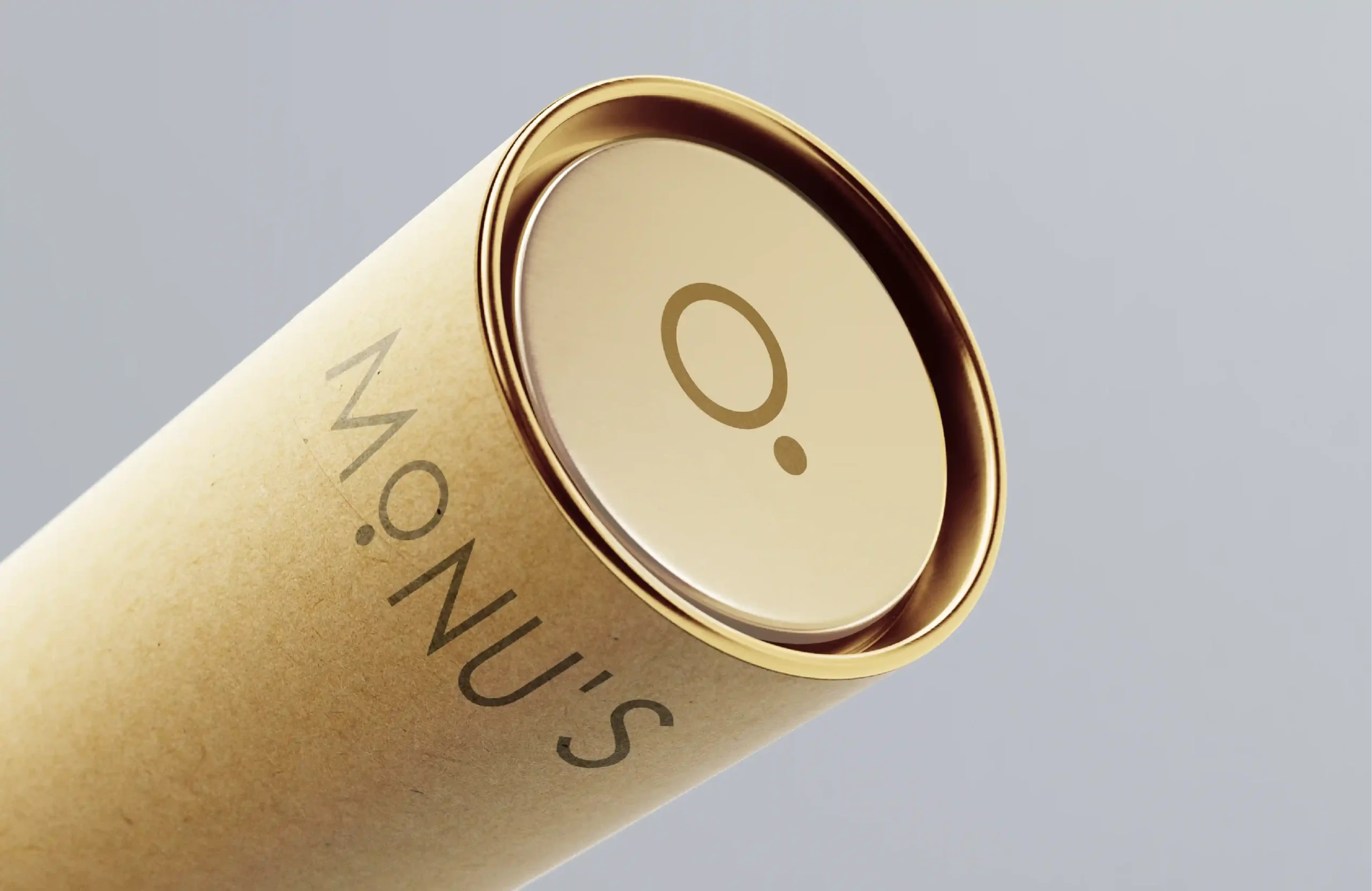 Close-up of MONU'S Art Studio kraft paper tube packaging with a metallic gold lid and minimalist logo.